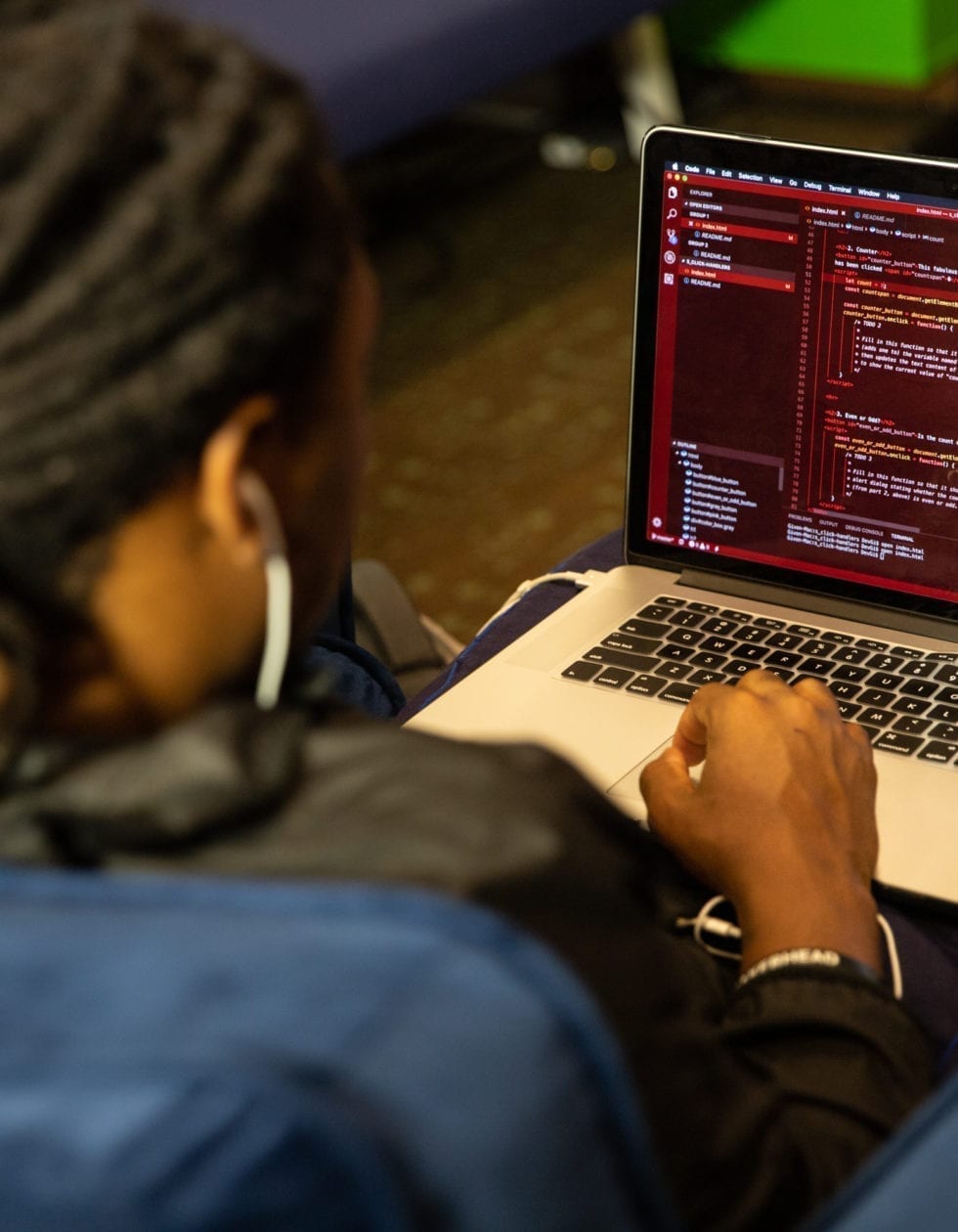 Over the shoulder photo of a male Kenzie Academy student working on code on his laptop.