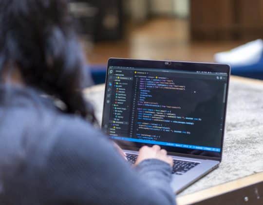 woman typing code on laptop