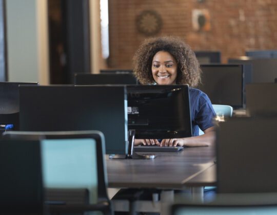 Woman coding on a desktop computer in a computer lab.